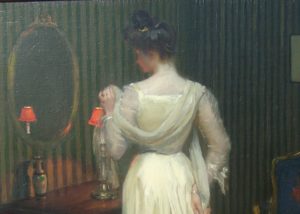 Charles Bittinger's Before the Mirror. Elegant woman dressed for an evening out stands in front of an oval mirror. White, long dress. The room's wall paper is green and white pinstripe.